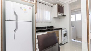 A modern kitchen with a refrigerator, oven, and microwave. - Madeira Aptos na Praia de Bombas (Bombinhas)