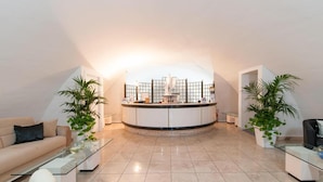 Una sala de estar moderna con un mostrador de recepción curvo, dos plantas en macetas, un sofá y una mesa de centro.