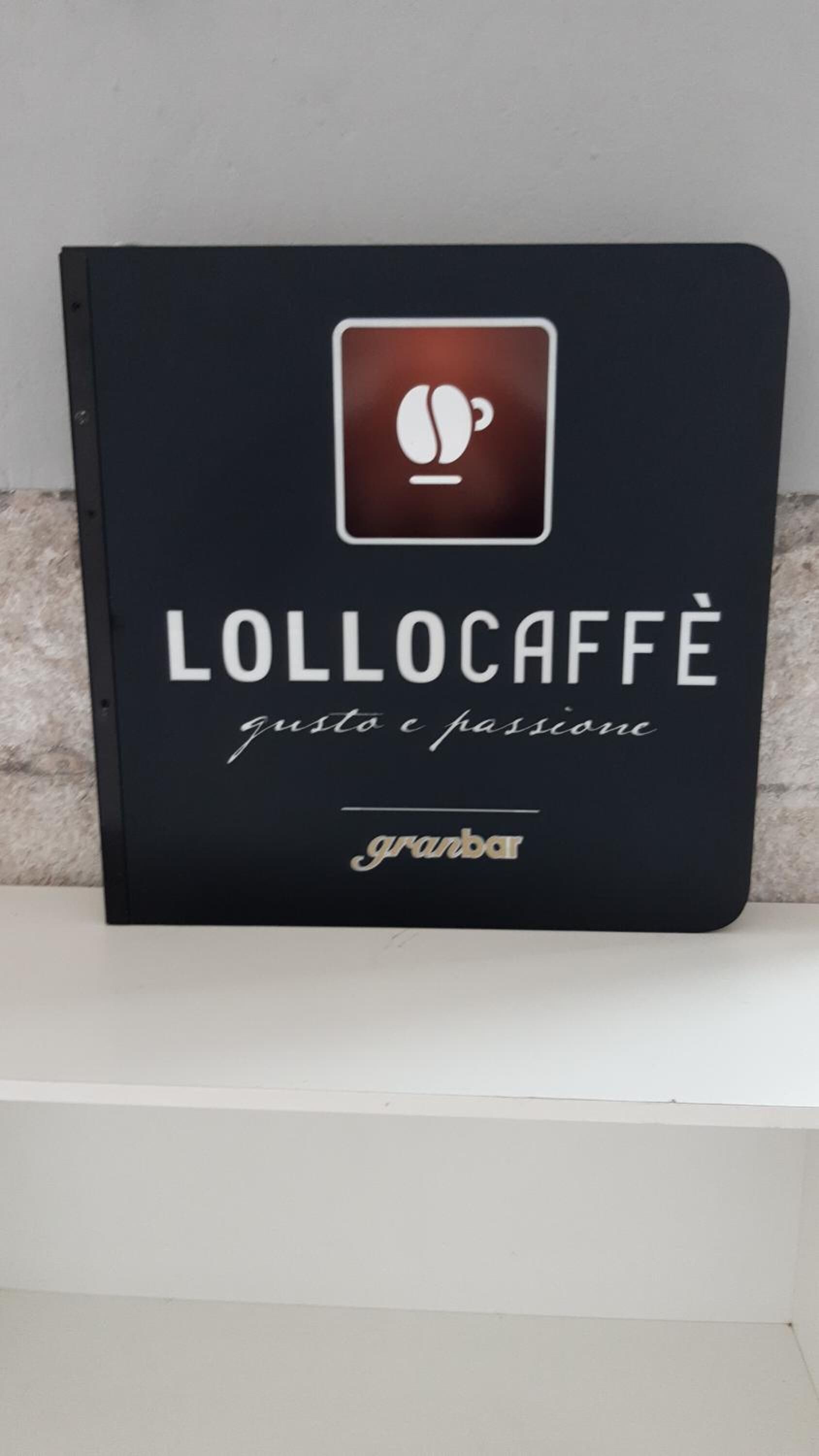 A black sign with a coffee cup icon, the text "LOLOCAFFÈ" and "granar" on a white background.