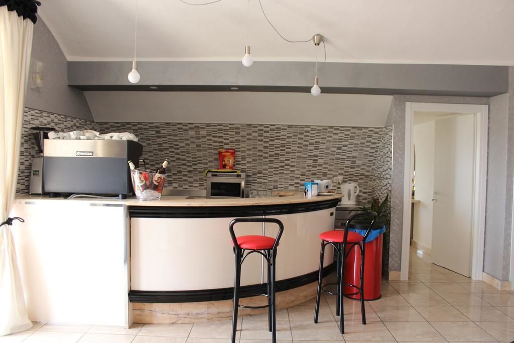 A modern kitchen with a curved island, stainless steel appliances, and red bar stools.