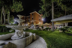 A courtyard with a fountain, outdoor seating, and a building in the background. - Il Postiglione (Minturno)