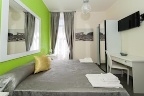 A hotel room with a bed, a desk, a chair, a TV, and a mirror. - Il Postiglione (Minturno)