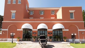 Un edificio grande de fachada roja, con tres entradas de arco y un carruaje en primer plano.