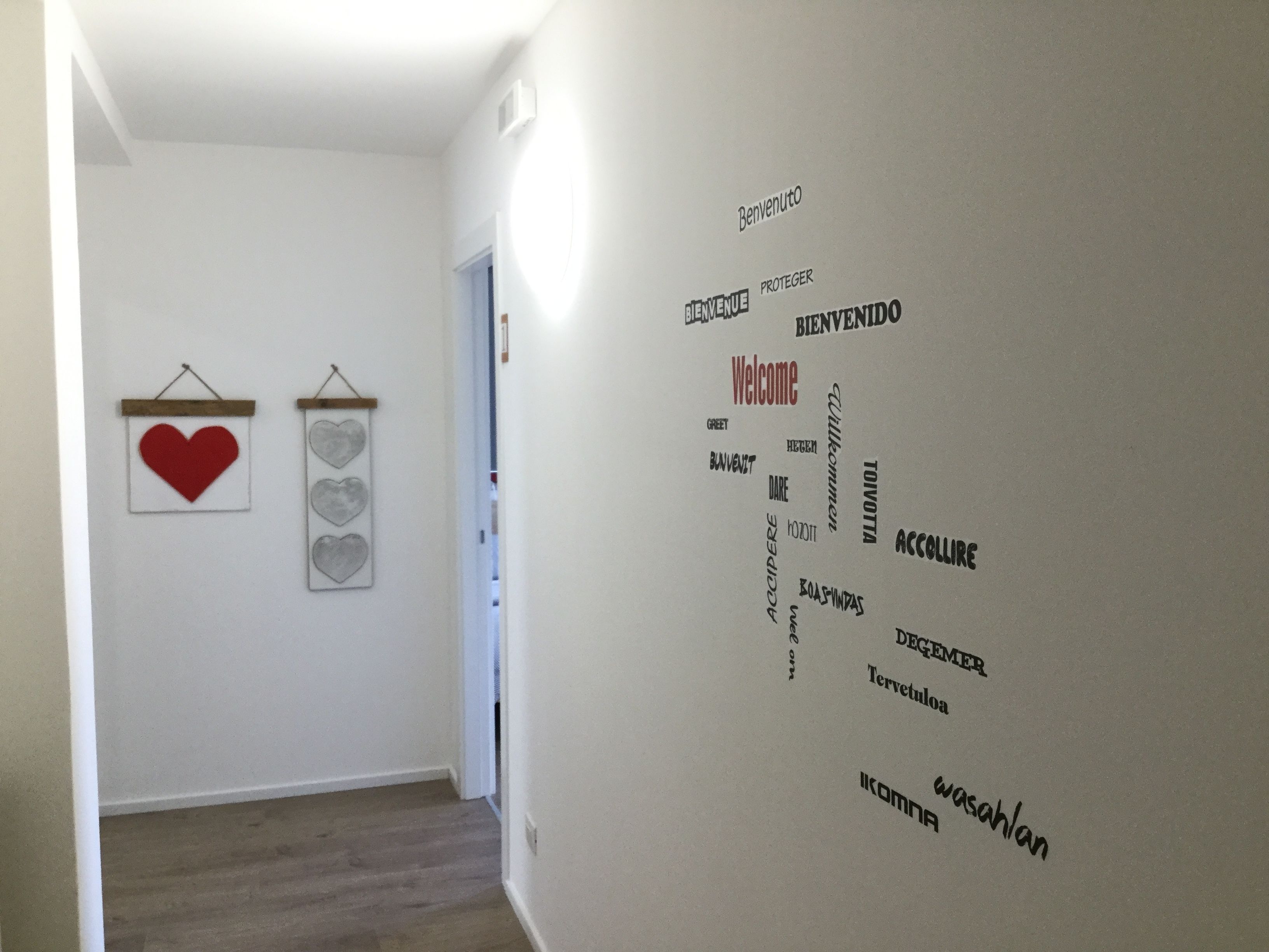 Un pasillo con un cartel de bienvenida en varios idiomas y dos adornos con forma de corazón.