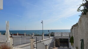 A coastal walkway with a metal railing, a street lamp, and a view of the sea. - Klaton Beach Hotel (Formia)