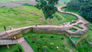 An aerial view of a historical site with stone walls, pathways, and a small bridge. - Momo Inn (Bogra)