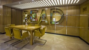 A modern reading area with a large 'READ' sign, a wooden reception desk, and a conference table with chairs. - Momo Inn (Bogra)
