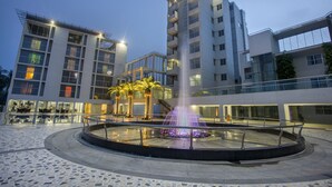 A modern building with a central fountain, surrounded by a circular plaza with a patterned floor. - Momo Inn (Bogra)