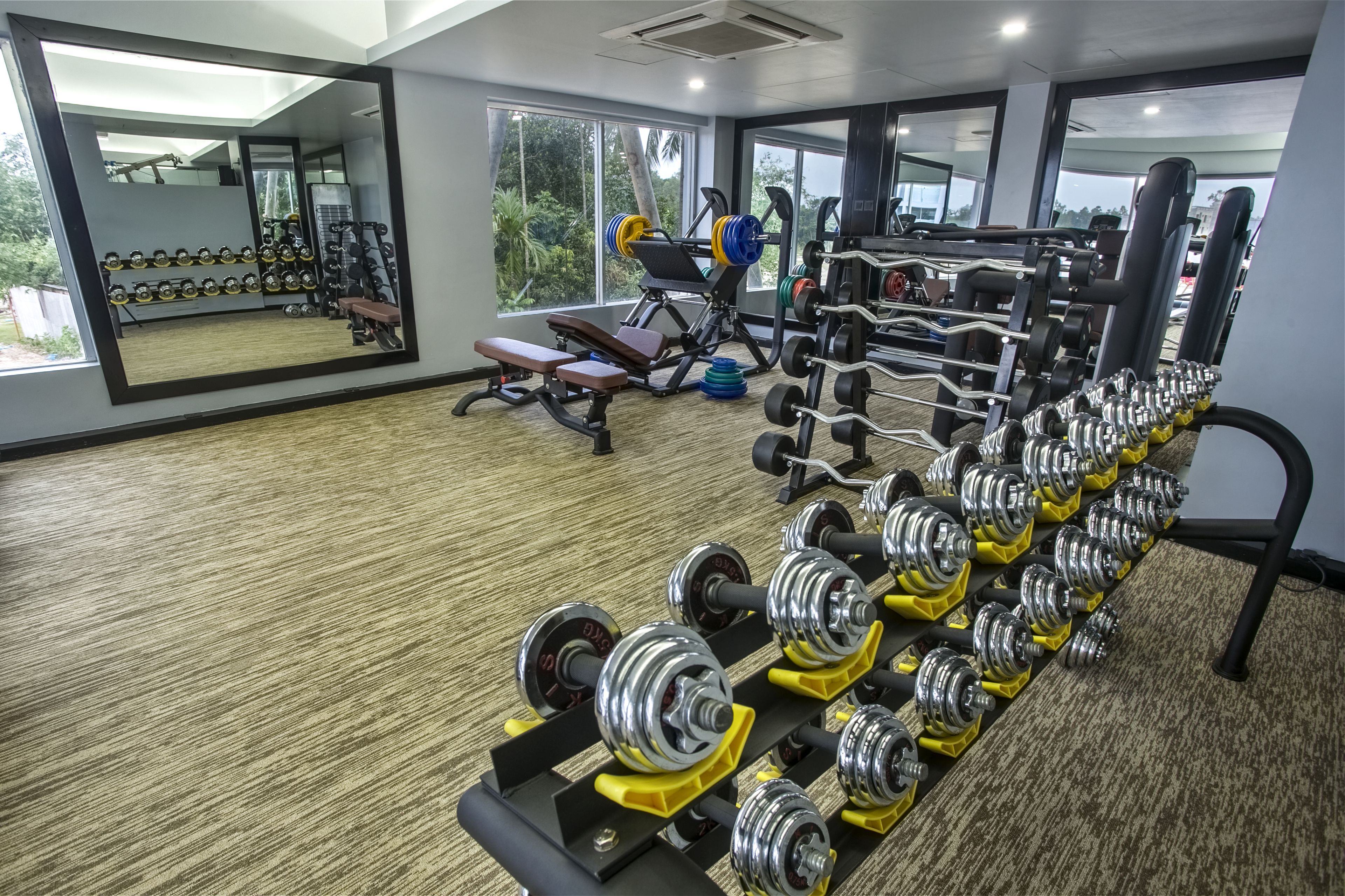 A gym with weightlifting equipment, benches, and a mirror.
