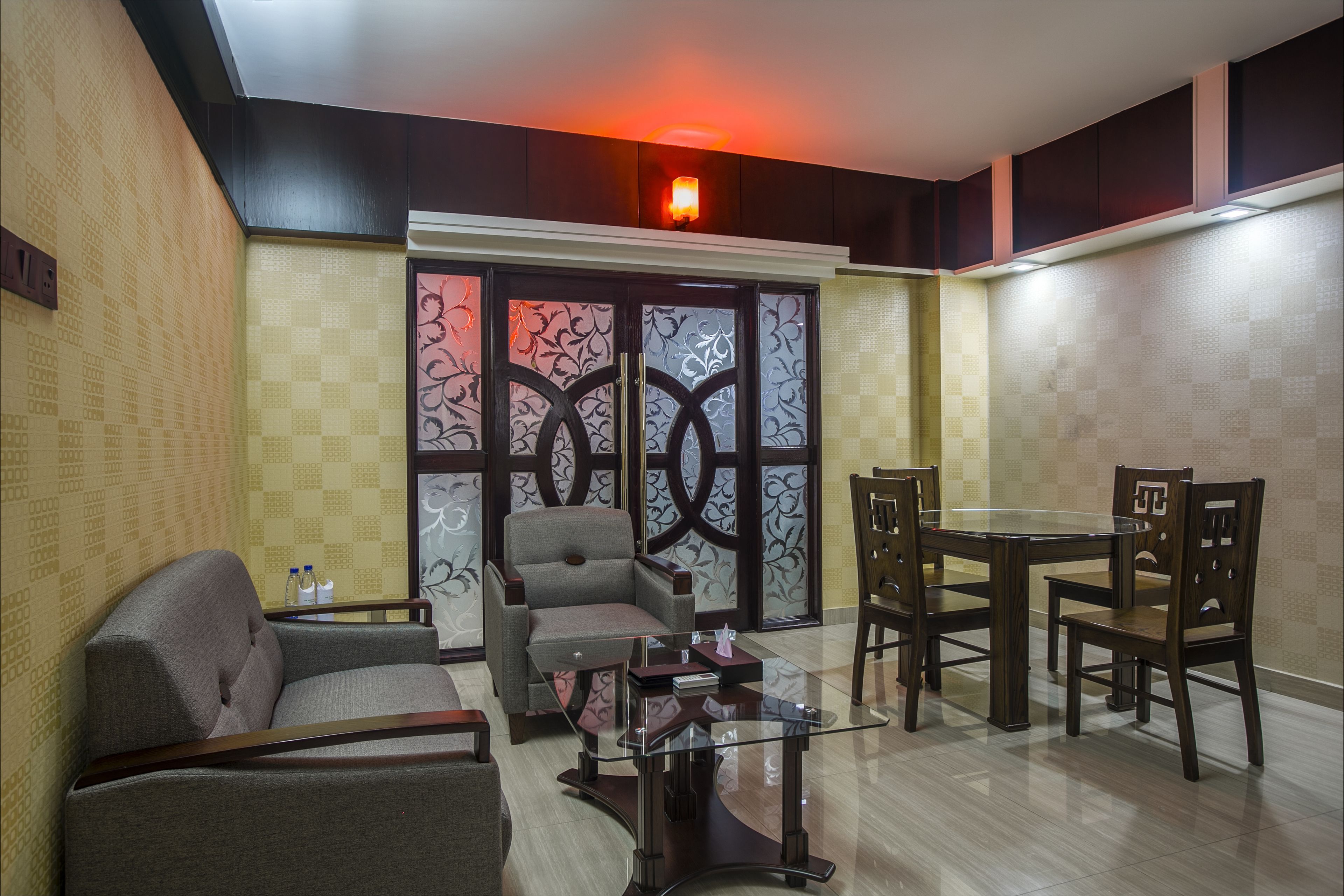 A modern living room with a sofa, armchairs, a glass coffee table, and a dining table with chairs.