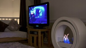 A bedroom with a television on a wooden stand, a circular white object, and a bed with pillows. - Bryn Melyn Farm Cottages- 5 Luxury Cottages In A Stunning Setting with Wood Fired Hot Tub (Bala)