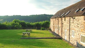 A stone building with a grassy courtyard, picnic tables, and a stone wall. - Bryn Melyn Farm Cottages- 5 Luxury Cottages In A Stunning Setting with Wood Fired Hot Tub (Bala)