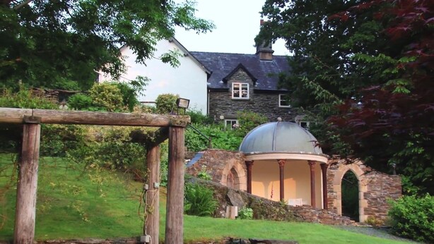 A stone structure with a dome, surrounded by greenery and a white building in the background. - Bryn Melyn Farm Cottages- 5 Luxury Cottages In A Stunning Setting with Wood Fired Hot Tub (Bala)