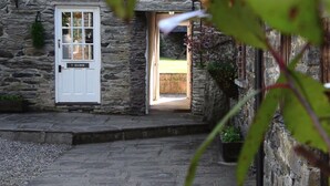 A stone building with a white door labeled "Y SCUBOR". - Bryn Melyn Farm Cottages- 5 Luxury Cottages In A Stunning Setting with Wood Fired Hot Tub (Bala)