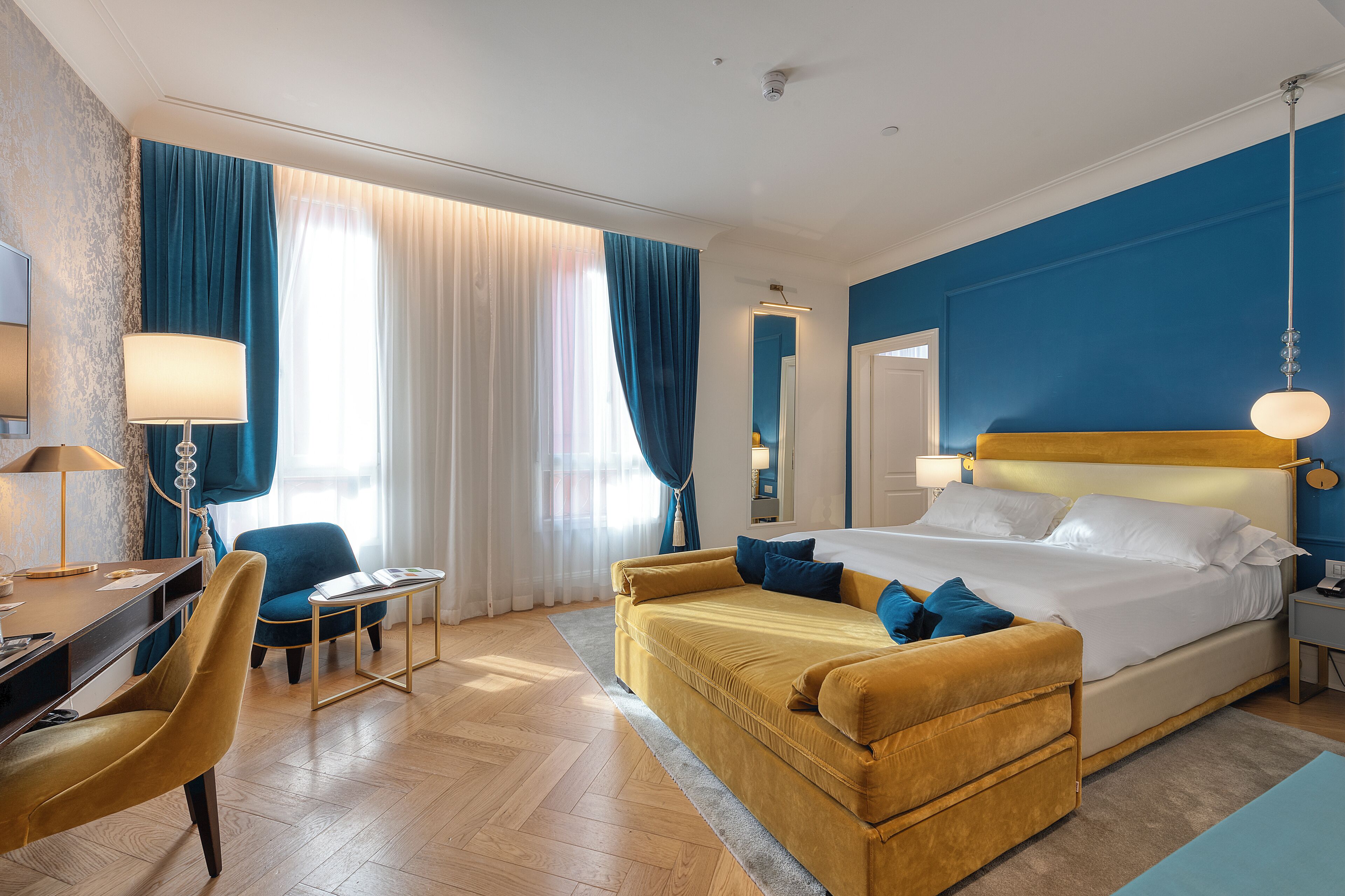 A hotel room with a bed, a desk, a chair, and a sofa.