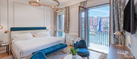 Habitación de hotel moderna con una cama grande, una zona de estar, un televisor y vistas a edificios a través de la ventana.