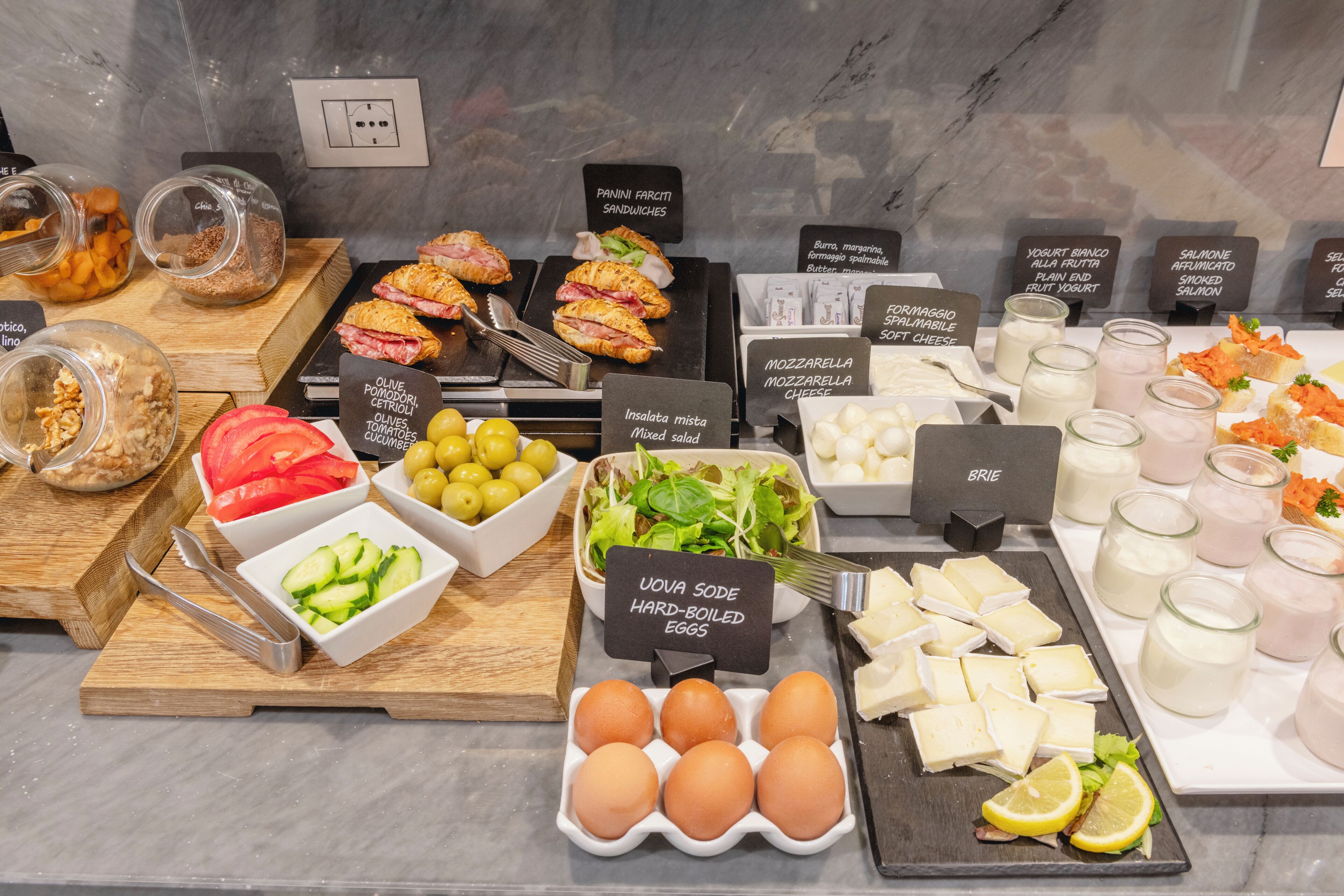 A buffet with various food options including sandwiches, salads, cheeses, and eggs.