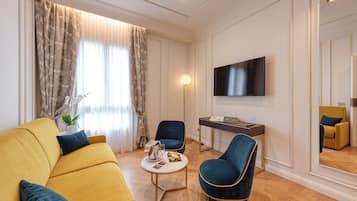 Una sala de estar moderna con un sofá amarillo, un sillón azul, una mesita redonda con una lámpara y un televisor de pantalla plana montado en la pared.