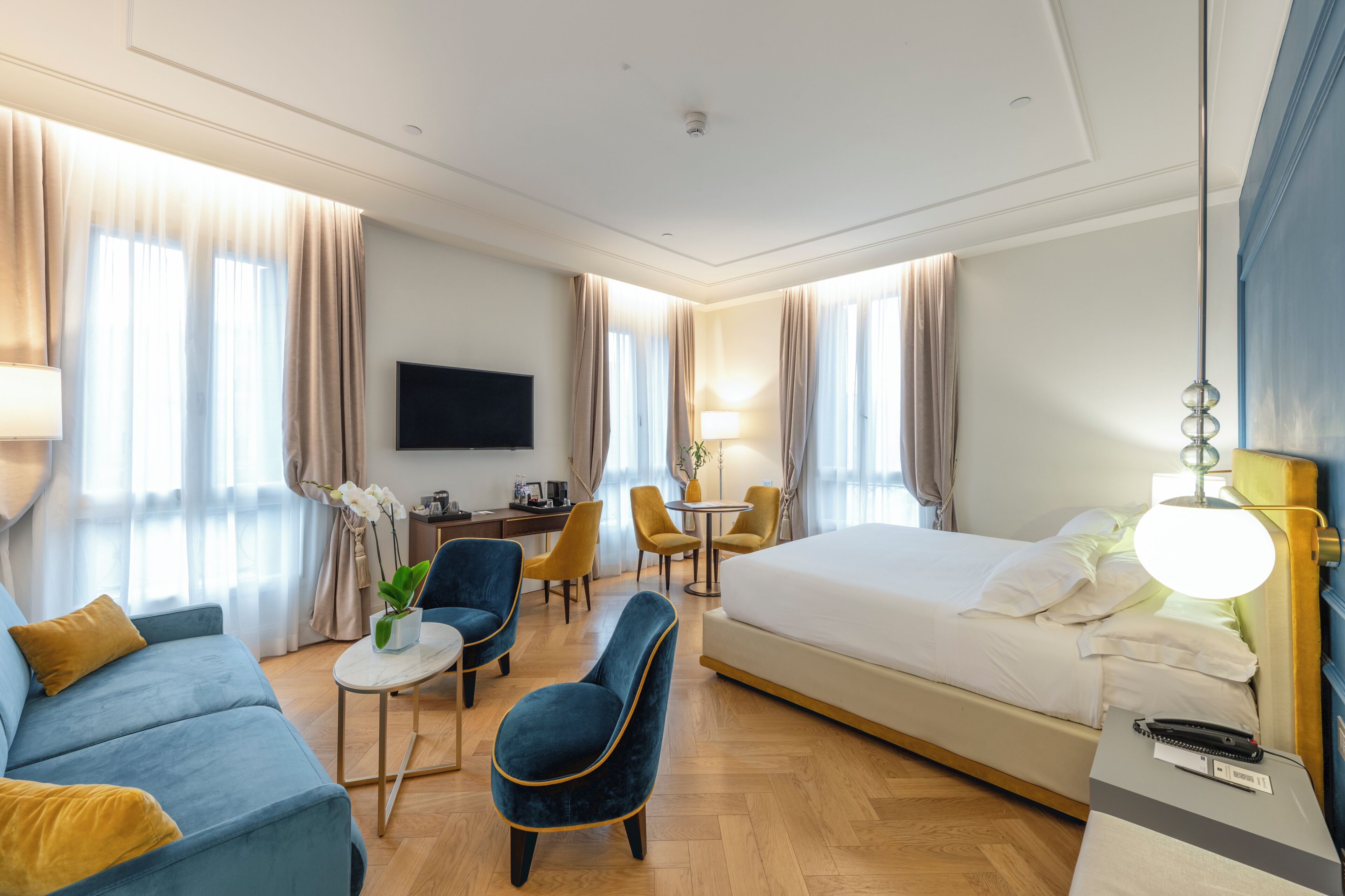 Een hotelkamer met een bed, een slaapbank, een bureau en een televisie.
