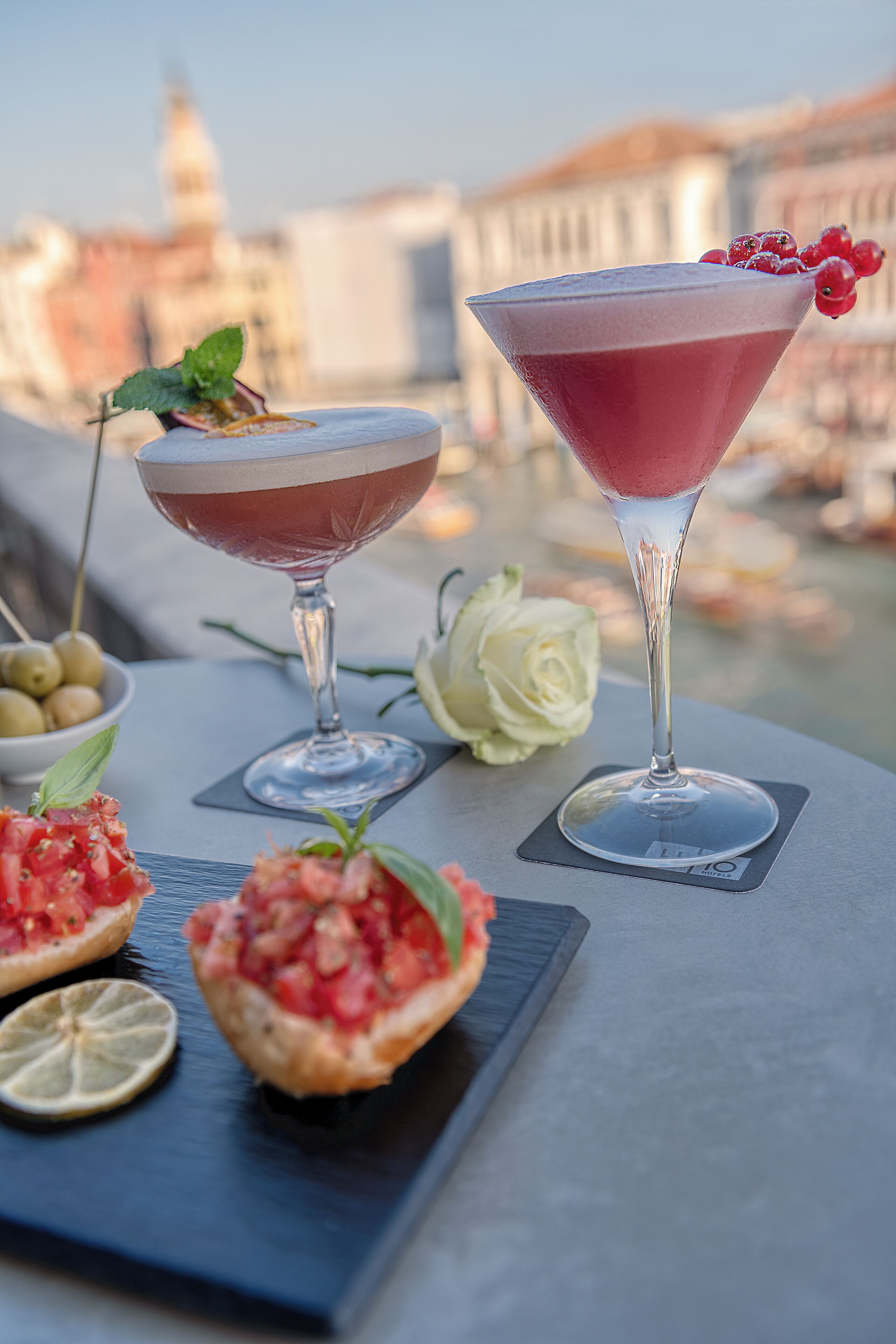 Deux verres à martini sur une table, avec une vue sur la ville en arrière-plan.