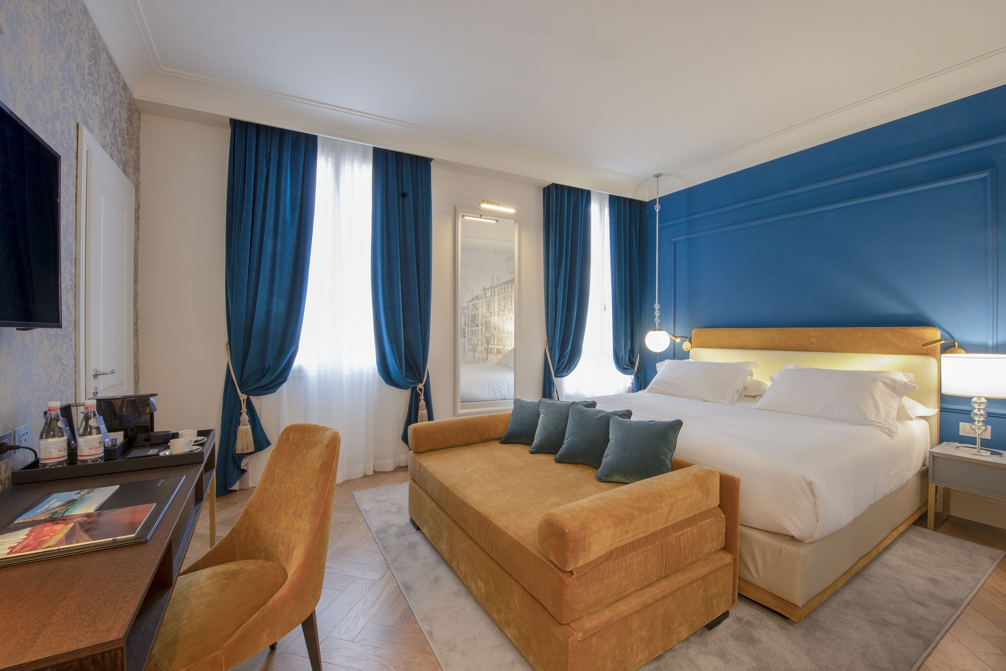 Une chambre d’hôtel avec un lit, un canapé, un bureau avec un ordinateur et une télévision.