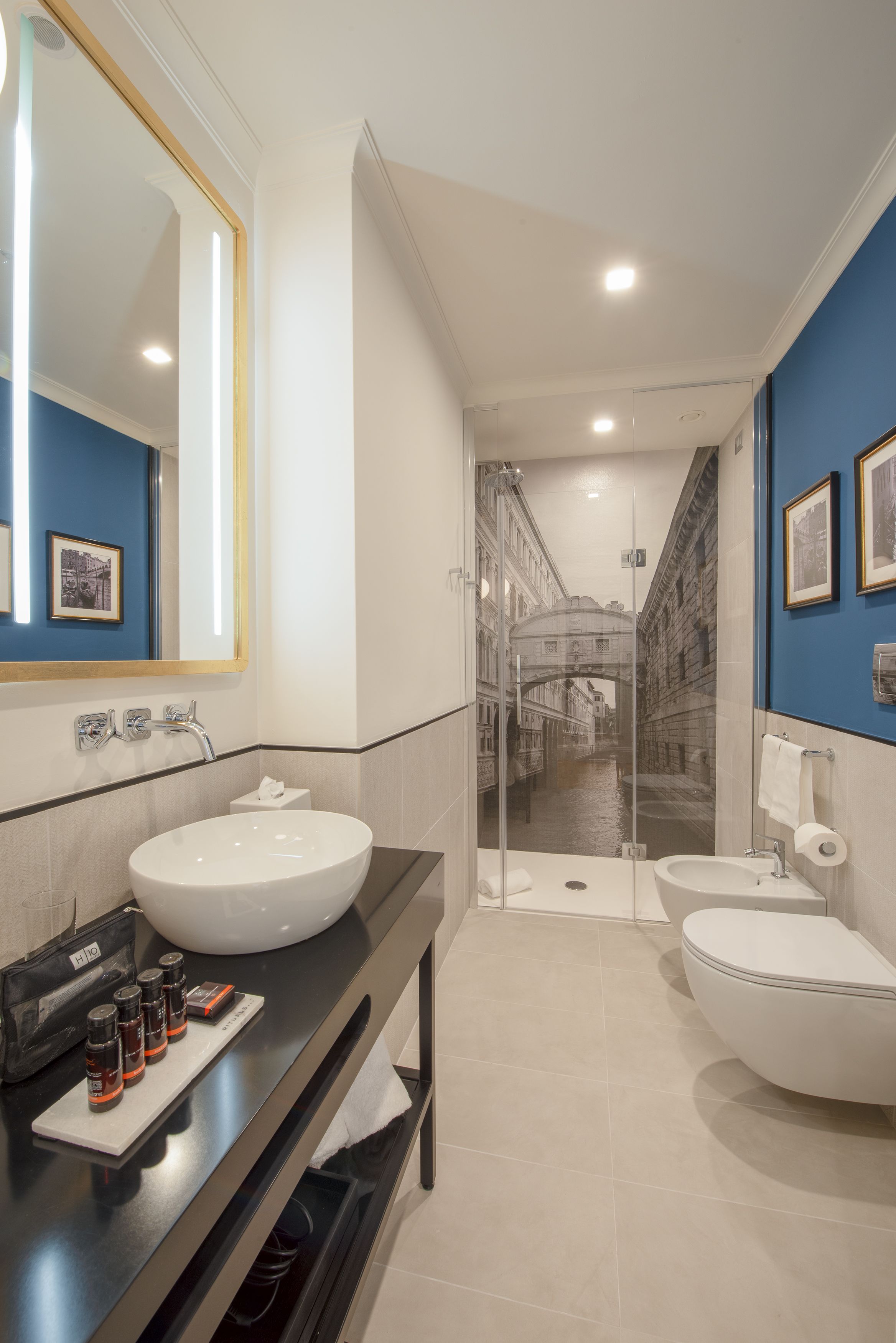 A modern bathroom with two sinks, a large mirror, and a glass shower enclosure.