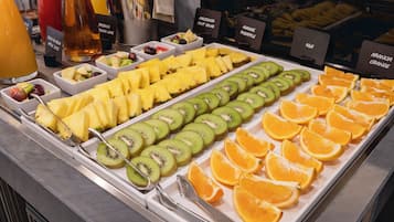 Monipuolinen aamiaisbuffet, jossa on tarjolla erilaisia hedelmiä ja mehuja.