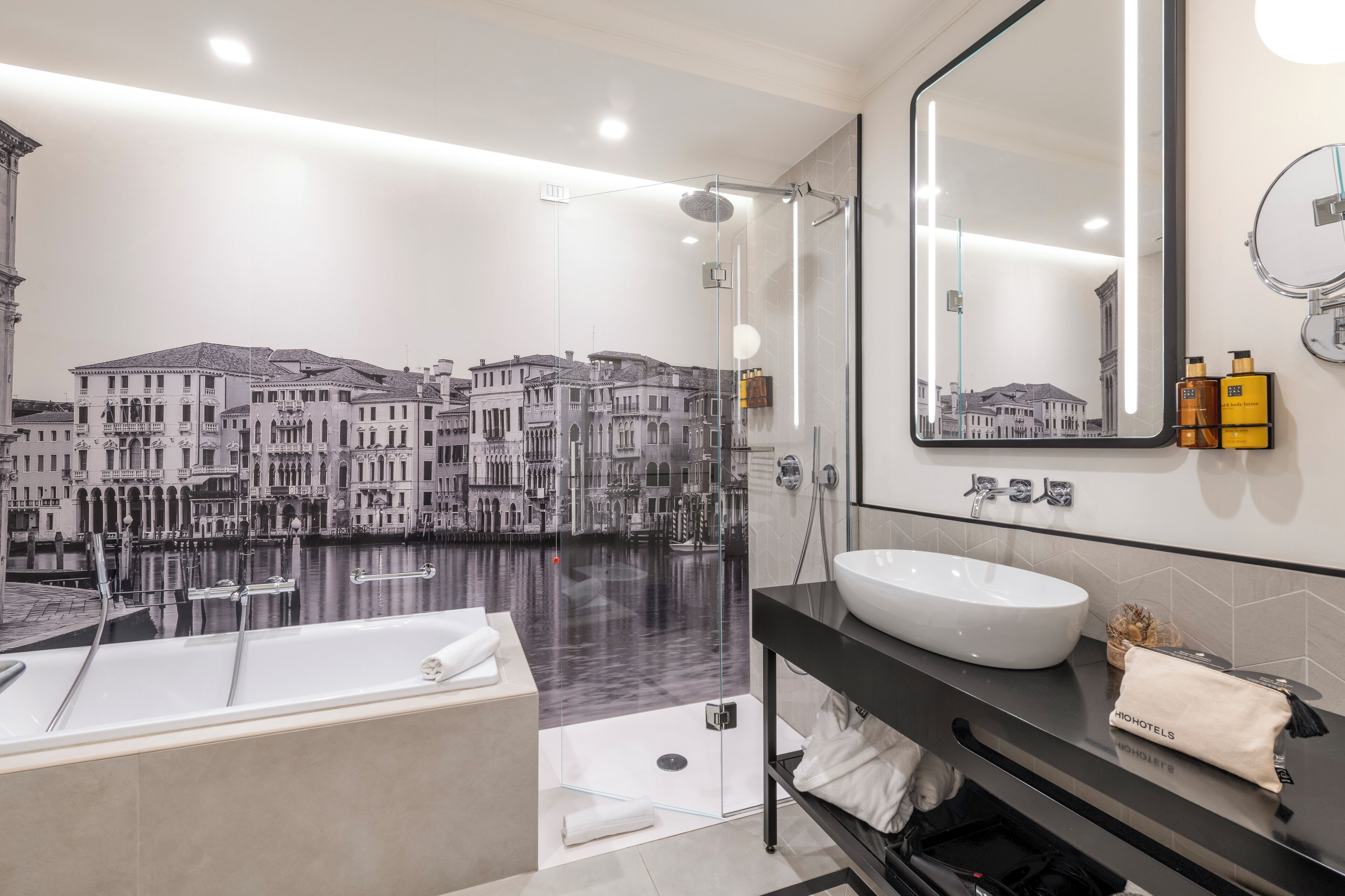 Un baño moderno con una bañera grande, una ducha con cerramiento de vidrio y un espejo amplio.