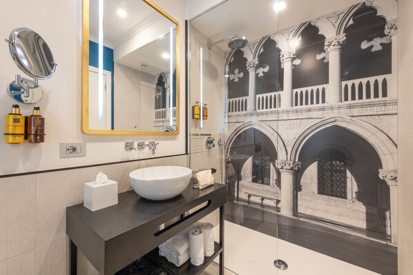 Un baño moderno con un espejo grande, un lavabo blanco y una ducha.