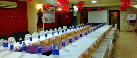 A conference room with a long table set for a meeting, balloons, and a projector screen.