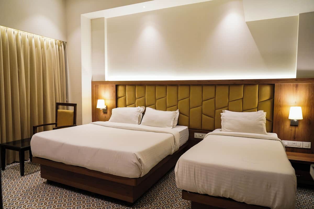 A hotel room with two beds, a chair, and a large window with curtains.