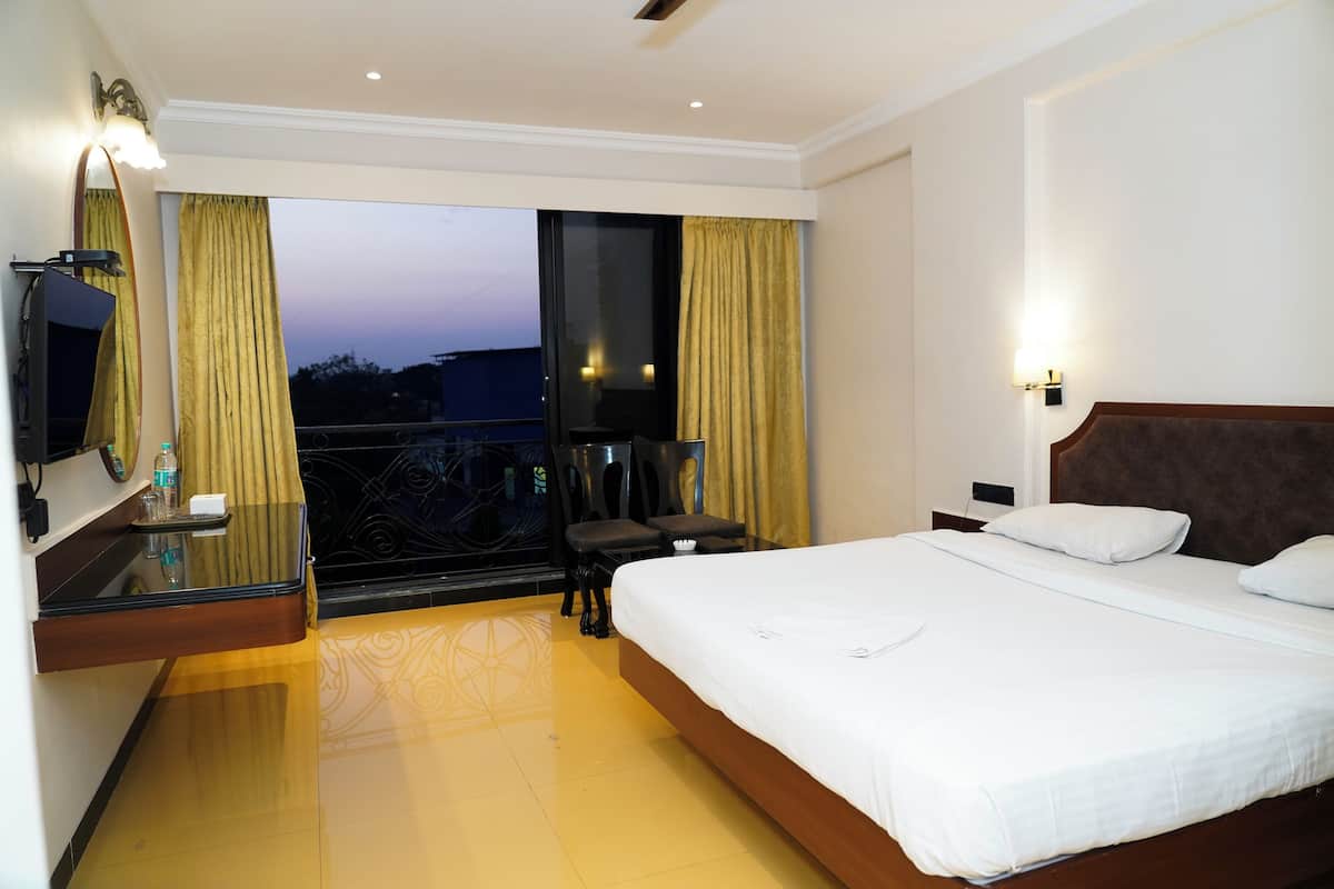 A hotel room with a large bed, a desk with a mirror, a chair, and a view of the outside.
