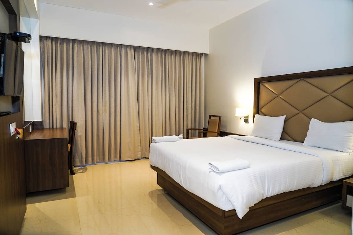 A hotel room with a large bed, a desk, and a chair.