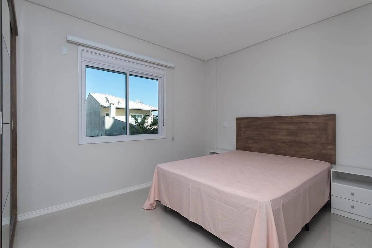 Un dormitorio con una cama individual, una ventana y un cabecero de madera.