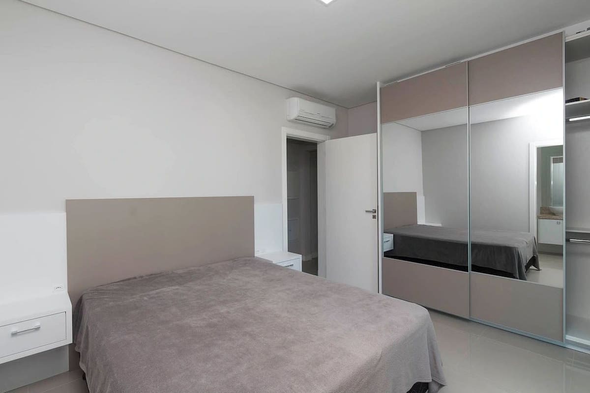 Un dormitorio con cama, armario y espejo.