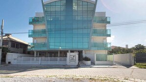 Un bâtiment moderne doté d’une façade en verre incurvée, de nombreux balcons et d’une entrée sécurisée par un portail.
