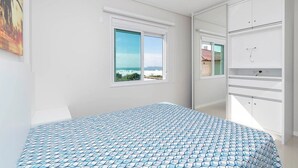 Une chambre à coucher avec un lit, une fenêtre donnant sur un beau paysage et une armoire.