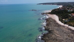 Vista aérea de una zona costera con playa, costa rocosa y edificios residenciales.