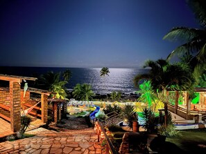 A beachfront resort with a stone pathway leading to a slide, palm trees, and a view of the ocean. - Pousada Enseada do Sol (Conde)