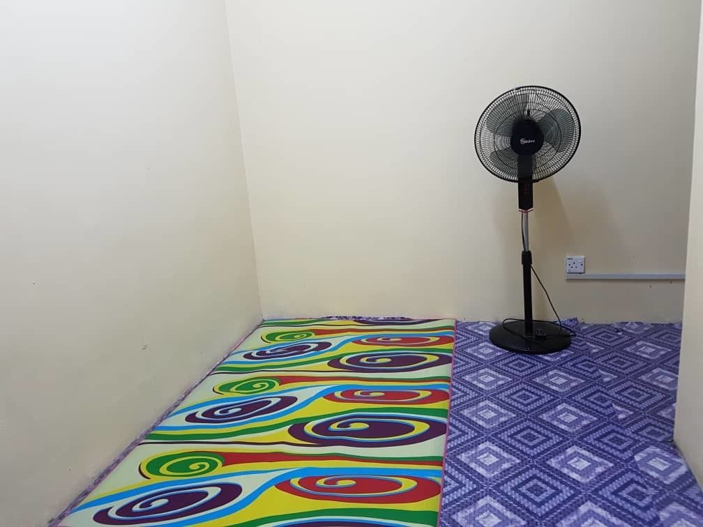 Una habitación con un tapete de colores, un ventilador de pie y una alfombra estampada.