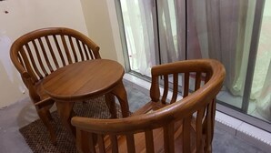 Ein Esszimmer-Set aus Holz mit einem runden Tisch und zwei Stühlen, platziert in der Nähe einer Glastür mit Vorhängen.