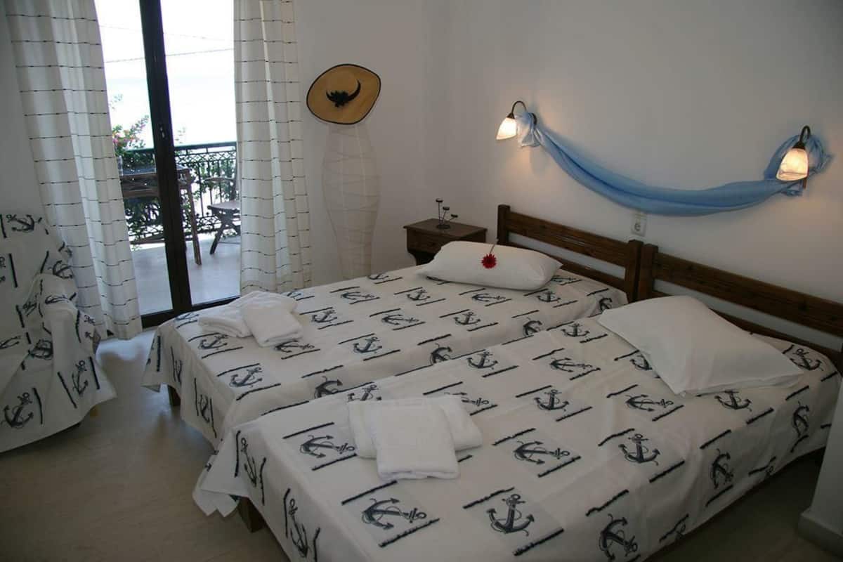 A hotel room with two beds, a balcony, and a view of the sea.
