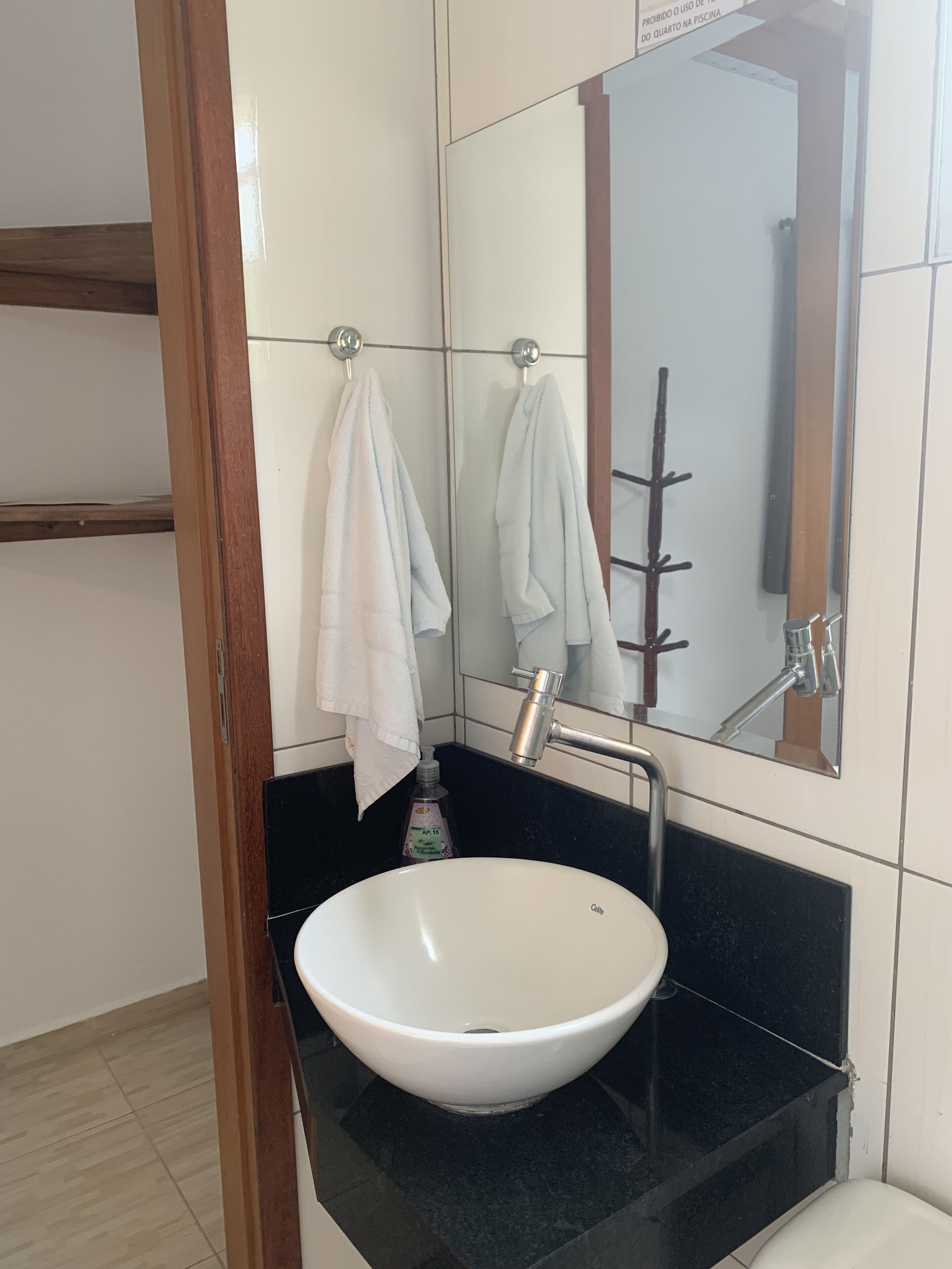 Un baño con lavamanos blanco, encimera negra y un espejo sobre el lavamanos.