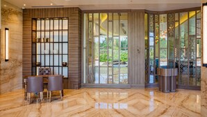 A lobby with a marble floor, a reception desk, and a seating area with chairs. - Nanu Resort, Arambol (Arambol)