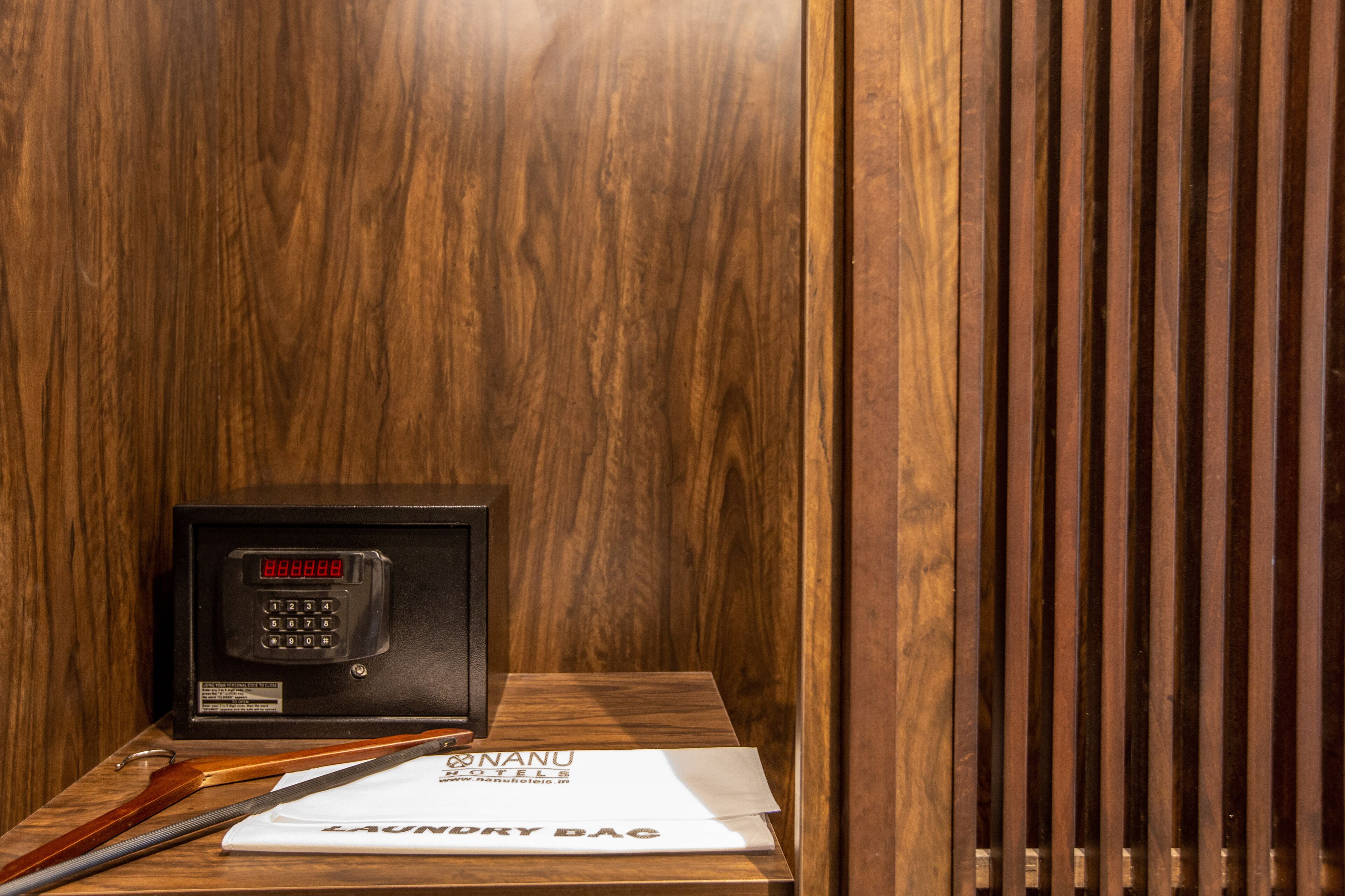 A wooden panel wall, a black electronic device with a keypad, and a white sign with text.
