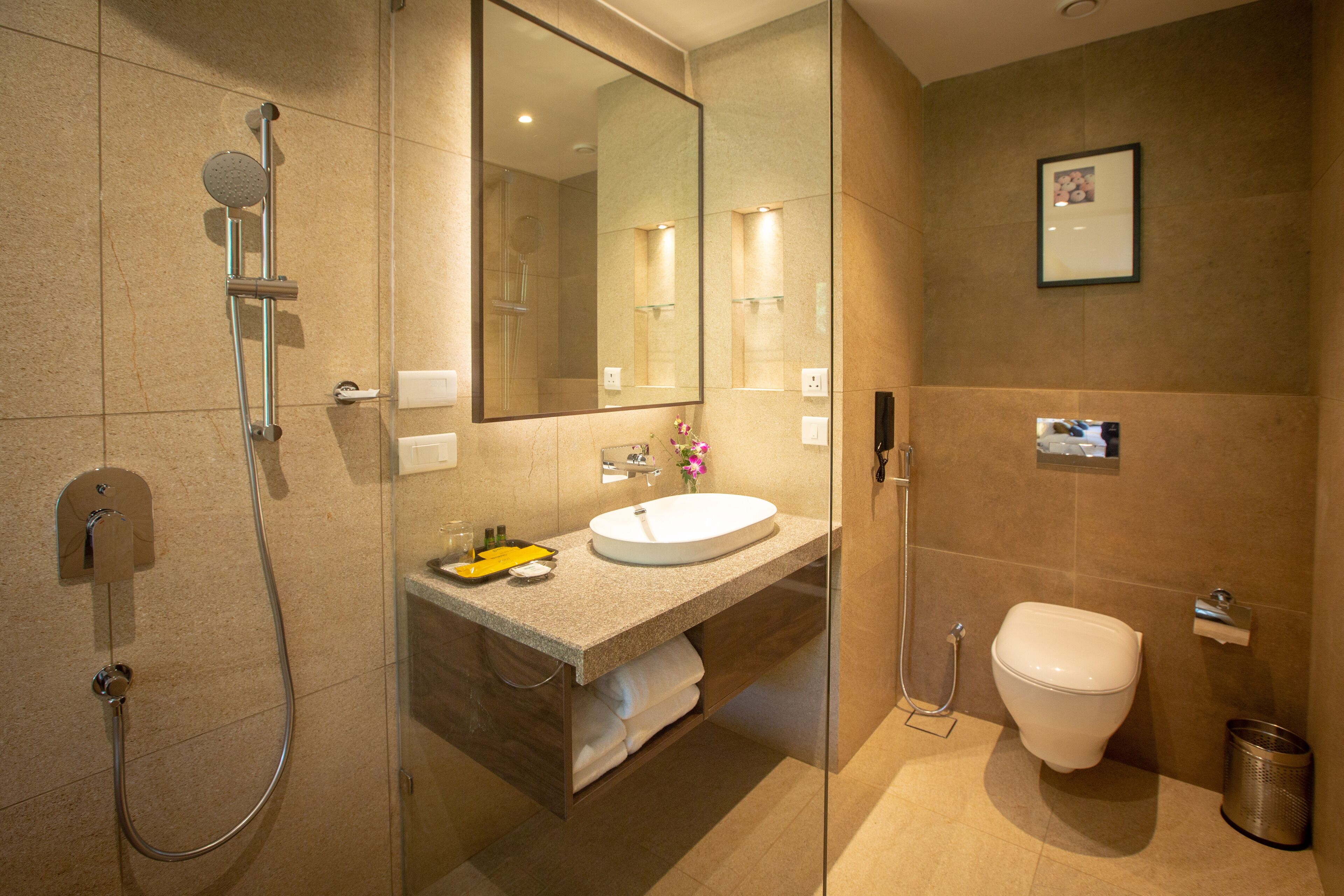 A modern bathroom with a glass-enclosed shower, a sink with a mirror above, and a toilet.