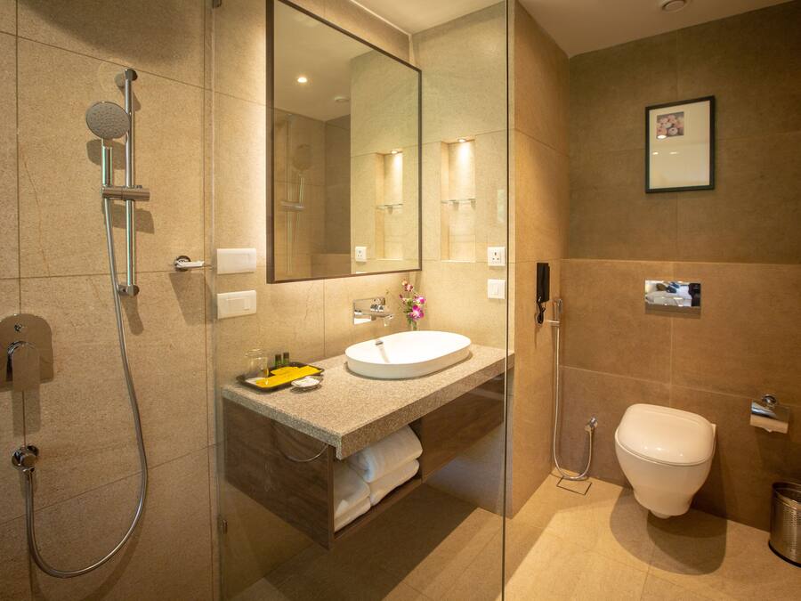 A modern bathroom with a glass-enclosed shower, a sink with a mirror above, and a toilet.
