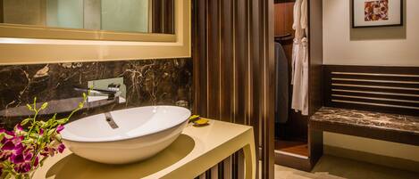 Une salle de bain moderne avec un grand lavabo blanc, un miroir et un vase de fleurs.