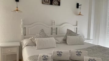 Una cama bien hecha con una colcha estampada y varios almohadones, incluyendo un juego con la marca 'Mare Hoteles'.
