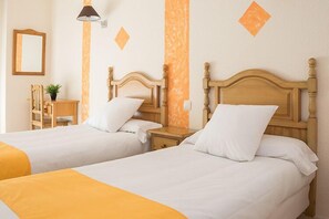 A hotel room with two single beds, wooden headboards, a nightstand, a lamp, and a small table with a chair. - Hotel Mare Estepona (Estepona)